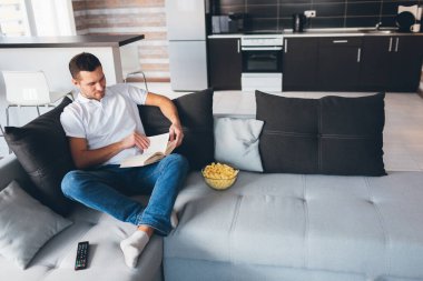 Genç adam kendi dairesinde televizyon izliyor. Odada tek başına kitap okuyan yakışıklı bir adamın fotoğrafı. Çalışıyorum ya da köylülere kitap okuyorum. Film izledikten sonra. Rahatla ve dinlen..