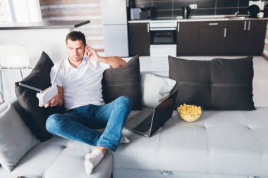 Genç adam kendi dairesinde televizyon izliyor. Adam kanepede oturup telefonla konuşuyor. Wi-fi yönlendiriciyi elinde tut ve şuna bak. İnternet aygıtı gümrükleniyor. Kanepede dizüstü bilgisayarını açtı..