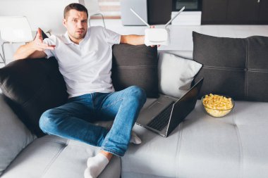 Genç adam kendi dairesinde televizyon izliyor. Kafası karışmış adam elinde kablosuz ağ yönlendiricisini tutuyor ve çalıştırmak ya da özelleştirmek için seksi olduğunu bilmiyor. Ayrıca açılan dizüstü bilgisayar.