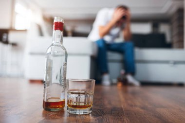 Genç adam kendi dairesinde televizyon izliyor. Adamın kanepeye oturup akşamdan kalma ya da baş ağrısı çektiği bulanık bir arka plan. Alkoliklerin sert içkilerle sorunları var..
