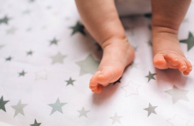 Yeni doğmuş bir bebeğin ayaklarına yakın çekim. Küçük bebek çocuk masasında yatıyor. Pencerenin yanındaki bebek masasında yeni doğmuş bir çocuk var..