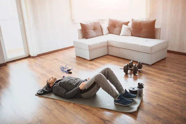 Ung vanlig man går in för sport hemma. Vanlig nybörjare liggande på matta på golvet och har vila. En riktig bild på en kille med vanlig kropp. Gå ner i vikt eller försöka hålla sig i form. — Stockfoto