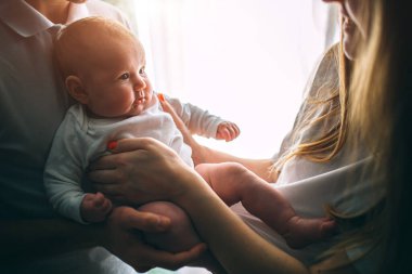 Anne ve baba kollarında bir bebek tutuyor. Bakım ve sağlık. Mutlu genç aile.