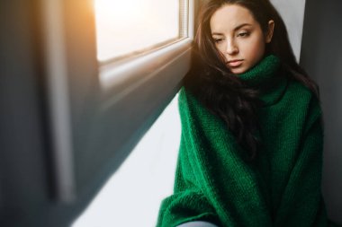 Mutsuz genç bir kadın pencerenin yanında üzgün. Esmer kadın ağlıyor. Üzüntü, ilgisizlik, depresyon ve melankoli..