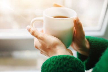 Fincan yakın plan. Kadın ve güzel atletik genç esmer kadın pencerenin yanındaki ahşap pencere eşiğinde oturuyor. Kadın model beyaz iç çamaşırı giyiyor. Şefkat ve sakinlik kavramı