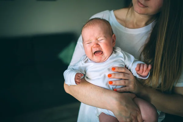 Retrato de um recém-nascido. A mãe tem um filho nos braços. Um recém-nascido está a gritar. Dor de estômago, cãibras na infância. Bebé recém-nascido a chorar. O primeiro ano de vida é inquieto . — Fotografia de Stock