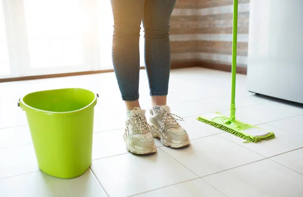 Young woman on kitchen during quarantine. Stand alone on clean floor after washing it with mop and water. Bucket on side. Daylight. — Stock Photo, Image