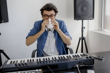 Adam hastalandı. Burnunu siliyor. Kayıt stüdyosundaki besteci. Müzik üretim teknolojisi. Adam kayıt stüdyosunda ses mikseri ya da yayın stüdyosunda DJ üzerinde çalışıyor..