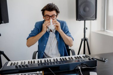 Adam hastalandı. Burnunu siliyor. Kayıt stüdyosundaki besteci. Müzik üretim teknolojisi. Adam kayıt stüdyosunda ses mikseri ya da yayın stüdyosunda DJ üzerinde çalışıyor..