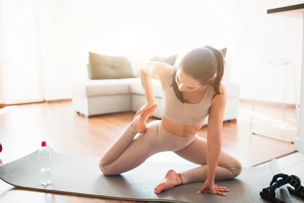 Ung kvinna som gör yoga träning i rummet under karantän. Stå i yogapose med böjda knän. Träning och träning hemma. — Stockfoto