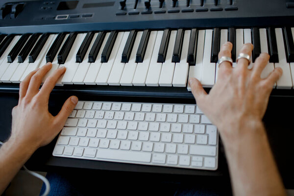 руки композитора на клавишах фортепиано в студии звукозаписи. Музыкальные технологии производства, человек работает на пианино и компьютерной клавиатуре на столе. концепция close up
.