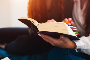 Çok renkli yer imlerinin olduğu kalın, büyük bir kitap var. Evde ya da öğrenci yurdunda ders çalışan iki kızıl saçlı öğrenci. Sınavlara hazırlanıyorlar..