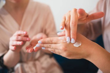 Eline krem sür. Havlu ve pijamalı iki genç kadın evde eğlenceli bir spa partisi veriyor..