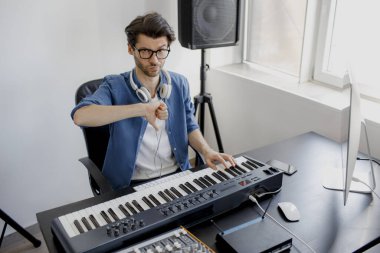 Başparmaklar aşağı. Kayıt stüdyosunda besteci elleri piyano tuşlarına basıyor. Müzik prodüksiyon teknolojisi, adam piyano ve bilgisayar klavyesi üzerinde çalışıyor. Kötü çalışan ve uzman. Hayal kırıklığına uğramış ve profesyonelliğe aykırı..