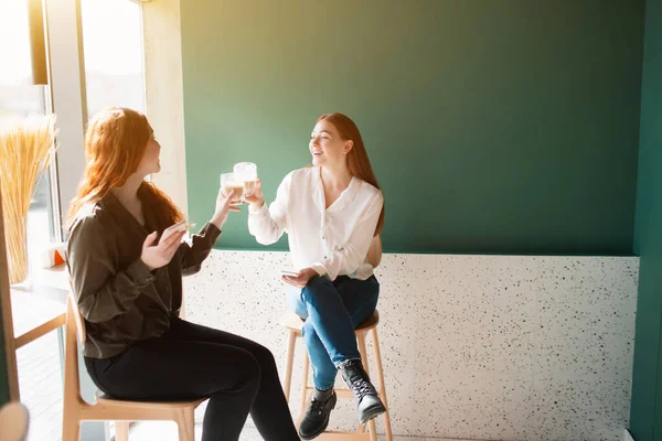 A női modellek kávét isznak egy kávézóban. A fiatal nők beszélnek és mosolyognak. — Stock Fotó