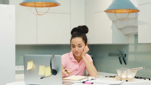 Mladá žena pracuje doma během karantény. Ospalý znuděný a unavený multitasking dívka pomocí notebooku a dělat si poznámky. Vyčerpaná multifunkční žena. — Stock video