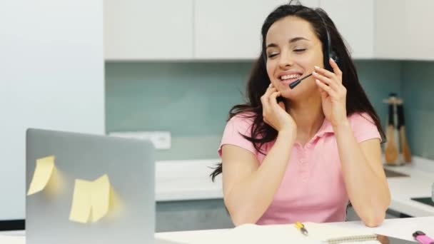 Jonge vrouw werkt thuis tijdens quarantaine. Call center help desk manager operator praten met glimlach tijdens vodeo conferentie. Heerlijk multitasking medewerker. — Stockvideo