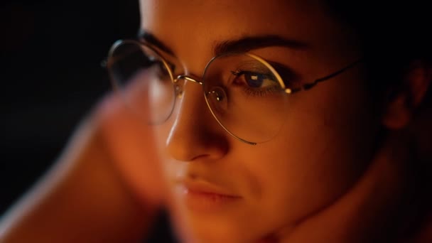 Ung kvinna hemma under karantänen. Närbild porträtt av en flicka med glasögon. Neon färger från orange till rött. — Stockvideo