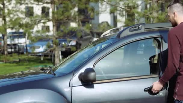 Jongeman in de auto. Kom dichterbij en ga zitten. Knappe hipster stak de sleutel in het contact slot en klaar om te rijden en te gaan voor een reis. Handen vast aan het stuur. — Stockvideo