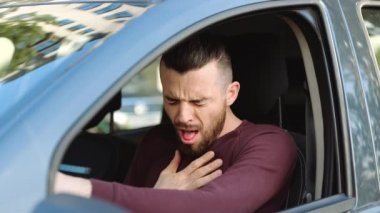 Arabanın içindeki genç adam. Hipster 'ın kotarma sorunu var. Göğsüm ağrıyor. Coronavirüs belirtileri gösteren hasta ve hasta biri. Yavaş çekim.