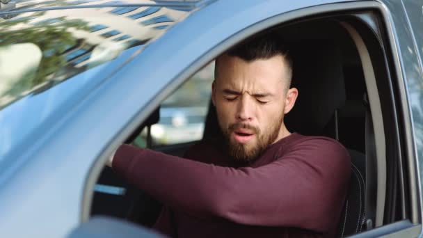 Jongeman in de auto. Hij zit voorin en schudt in de hand. Lijden aan sterke pijn in de keelpijn. Zieke persoon in de auto. Voorzichtig in slow motion. — Stockvideo