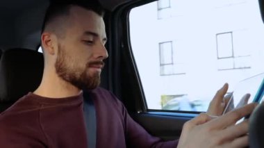 Arabanın içindeki genç adam. Arka koltuğa otur ve tablet kullan. Seyahat sırasında ya da küçük bir gezi sırasında oynamak ya da çalışmak. Taksi ya da personel aracının içinde..