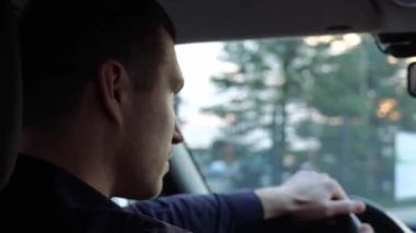 Arabanın içindeki genç adam. Sürücü dikkatli sürsün. Yoğunlaşmış adam direksiyona el ele tutuşup ileriye bakıyor. Arka plan.