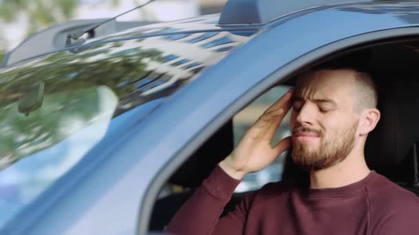 Un joven dentro del auto. Hispter estornuda y sufre de dolor de cabeza. Mano conmovedora. Enfermo enfermo en el coche. Síntomas del coronavirus . — Vídeos de Stock