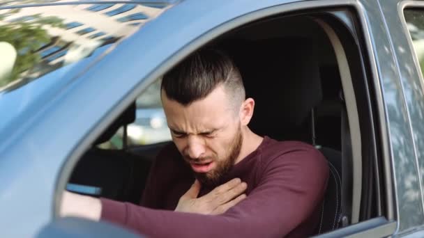 Mladý muž v autě. Chlápek se chechtá a drží se za ruku na hrudi. Sedět sám v autě a trpět bolestí. Koronavirové příznaky. — Stock video