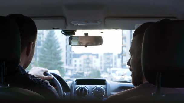 De jeunes hommes dans la voiture. Monter ensemble et parler. Jolie conversation entre amis. Équitation dans la ville parmi les grands bâtiments . — Video