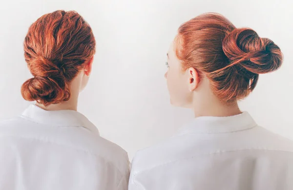 Zwei rothaarige Schwestern stehen isoliert auf weißem Grund in Hemden. Frauen zeigen den Rücken. Haare werden zu einem Bündel verdreht. Sie haben glatte Haare und lockige Locken. — Stockfoto