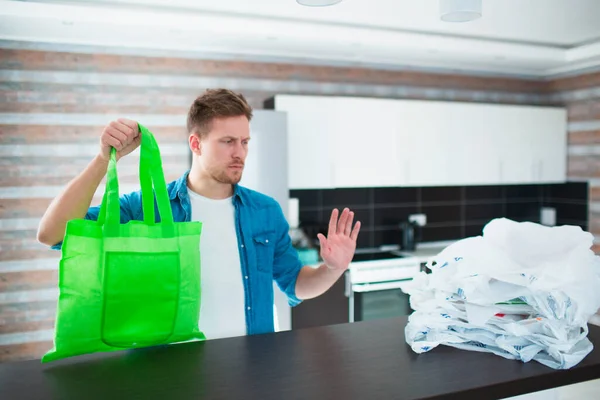 Concept against unreasonable use of plastic bags. Use a reusable bag - save nature from microplastics. Young man chooses an eco bag — Stock Photo, Image