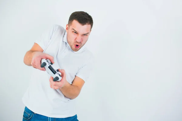 Young man isolated over white background. Active guy playing games during quarantine. Hold joystick with both hands during intense match. — Stock Photo, Image