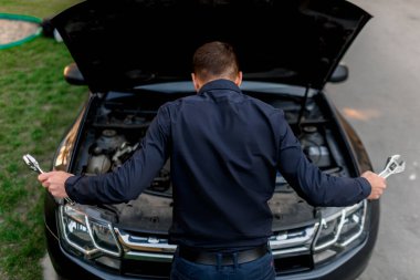 Araba arızası konsepti. Araba çalışmayacak. Genç adam her şeyi kendi düzeltmeye çalışıyor. Arabayı kendi başlarına tamir edemezler. Sigorta tüm masrafları karşılamalı..