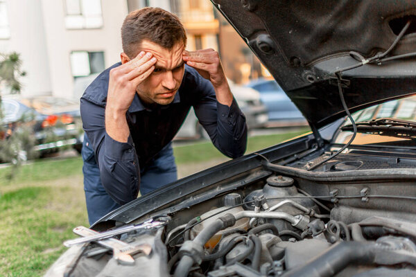 Car breakdown concept. The car will not start. The young man is trying to fix everything himself. They cannot fix the car on their own. Insurance must cover all costs.