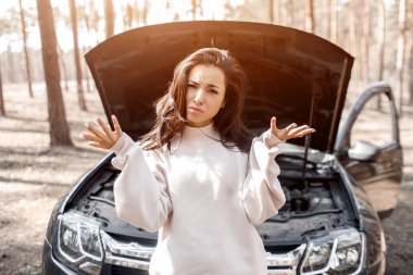 Araba arızalandı. Yoldaki bir kaza. Kadın kaputu açtı ve motoru ve arabanın diğer parçalarını kontrol etti. Kameraya bakıyor ve ne yapacağını bilmiyor..