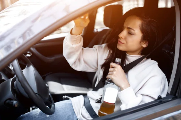 Dricker vid ratten. En full kvinna kör bil. Livshotande att dricka alkohol och köra bil. — Stockfoto