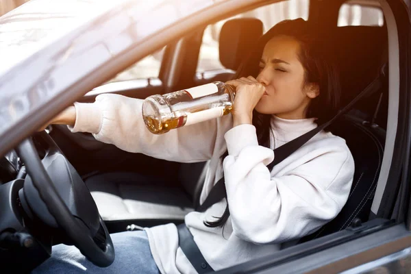 Пьет за рулем. Пьяная женщина водит машину. Жизнь угрожает выпивкой и вождением автомобиля . — стоковое фото