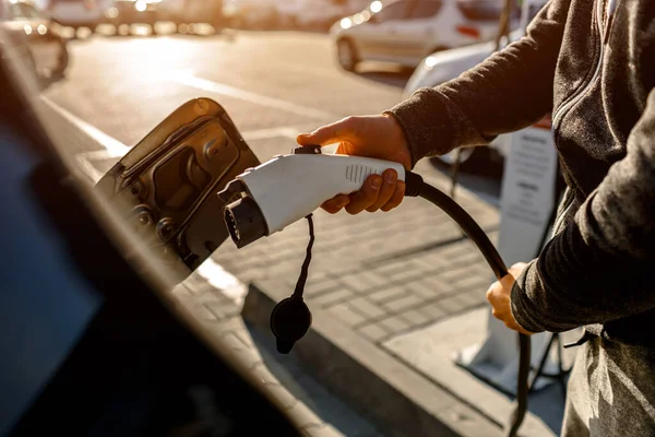 Dışarıdaki otoparkta elektrikli araba için elektrik kablosu. Ve arabayı alışveriş merkezinin yanındaki park yerindeki şarj istasyonuna bağlayacak.
