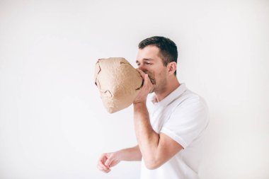 Genç hasta bir adam beyaz arka planda izole edilmiş. Adam torbaya kusuyor. Sindirim sorunu var. Mide ağrısından muzdarip.