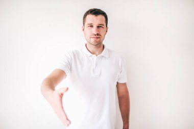 Genç adam beyaz arka planda izole edilmiş. Adam titremek için el ele tutuşmuş. Stüdyoda yalnız neşeli, pozitif adam..