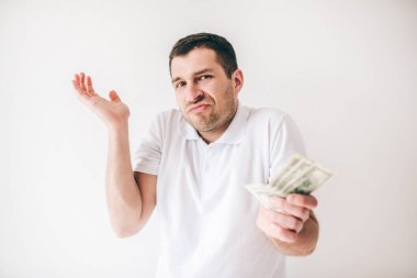 Genç adam beyaz arka planda izole edilmiş. Adam merak ediyor bir elini biraz yukarı kaldırıyor. Faturalar başka bir elde. Verilen para.