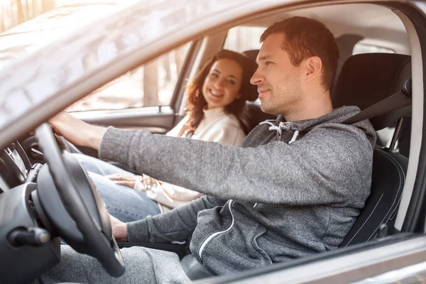 Happy young family monta em um carro na floresta. Um homem está dirigindo um carro, e sua esposa está sentada nas proximidades. Viajar de carro conceito — Fotografia de Stock