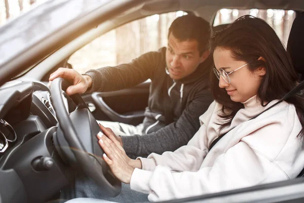Instrução de condução. Uma jovem aprende a dirigir um carro pela primeira vez. Ela não funciona bem. Seu marido ou instrutor grita com ela. Ela está a chorar. — Fotografia de Stock