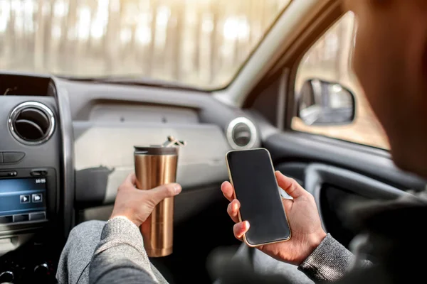 Primo piano di mani e thermos con smartphone in auto. Concetto di viaggio — Foto Stock