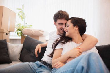 Genç ve mutlu bir çift yeni bir daireye taşınır. Kanepede oturuyorlar ve yeni evlerine bakıyorlar..