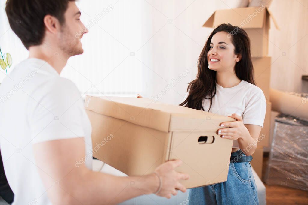 Young couple carrying big cardboard box at new home.Moving house.