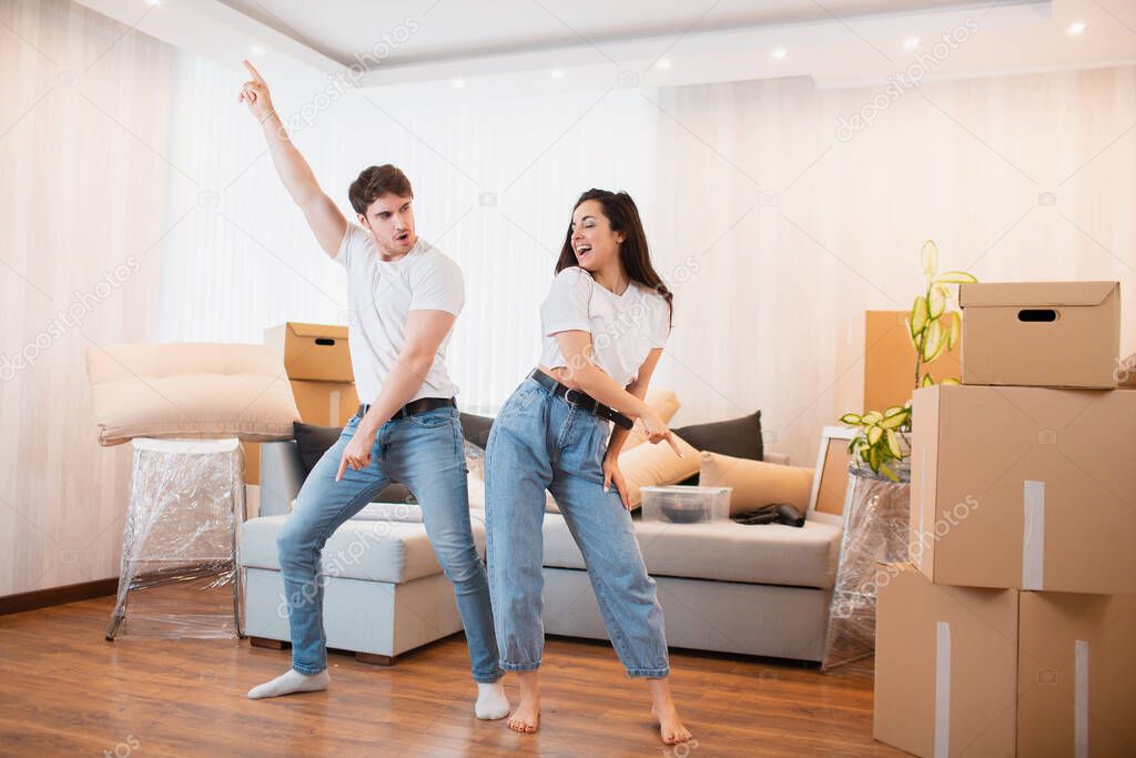 H appy husband and wife have fun swirl sway relocating to own apartment together, relocation concept. Overjoyed young couple dance in living room near cardboard boxes entertain on moving day,