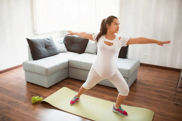 En gravid kvinna tränar på en yogamatta hemma. Graviditet och idrott. Oga och Pilates för gravida kvinnor. Graviditetens tredje trimester — Stockfoto
