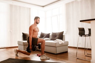 Genç, sıradan bir adam spor olsun diye evine gidiyor. Tişörtsüz bir sporcunun ayağa kalkıp yere çömelmesi ve dambılları elinde tutması. Antrenmana başlamaya hazırım. Sıradan bir adam üzerinde çalışır